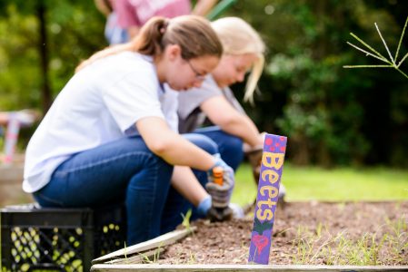 Girl working in a garden planting vegetables during an annual service day called Ripple Effect